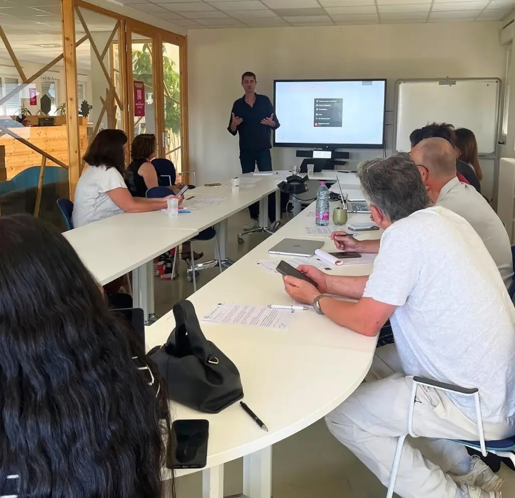 Formateur animant une session de formation en présentiel devant un groupe d'apprenants.